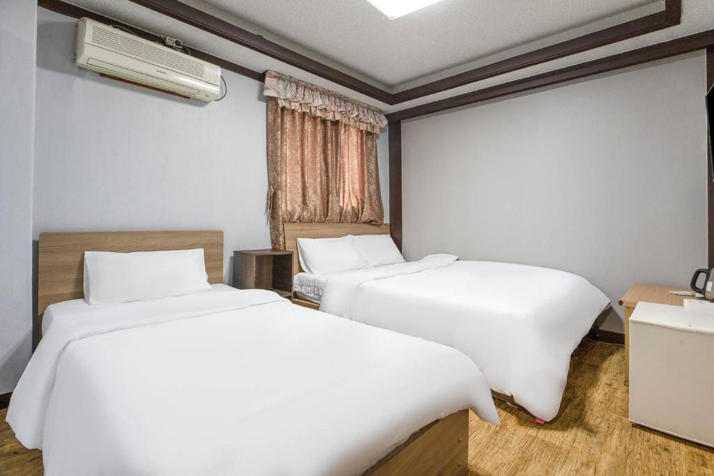 two beds in a room with white sheets at Keumkang Motel in Seoul