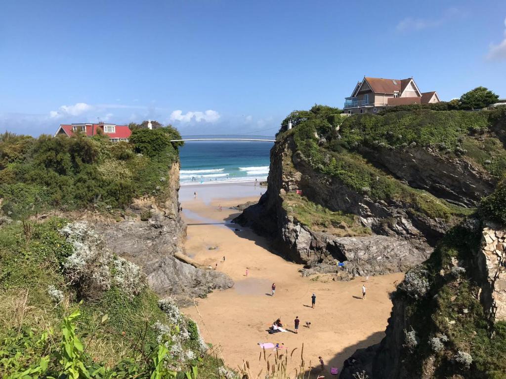 a group of people on a beach between two cliffs at The Quies in Newquay