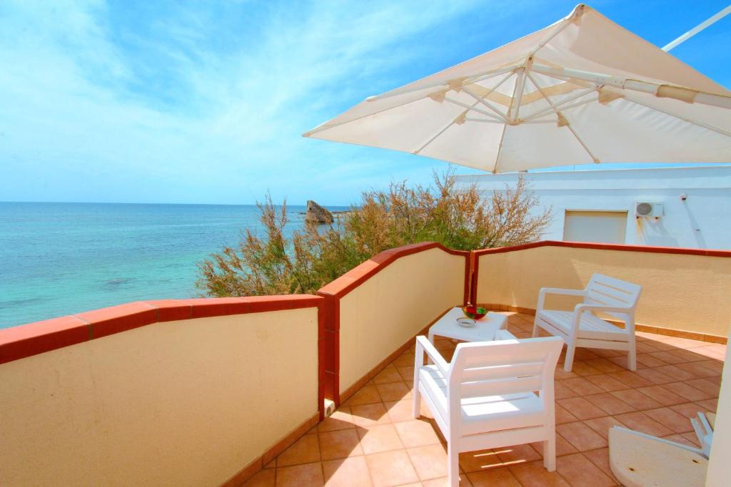 un patio con ombrellone, sedie e oceano di Beach Apartment in Puglia a Torre Pali