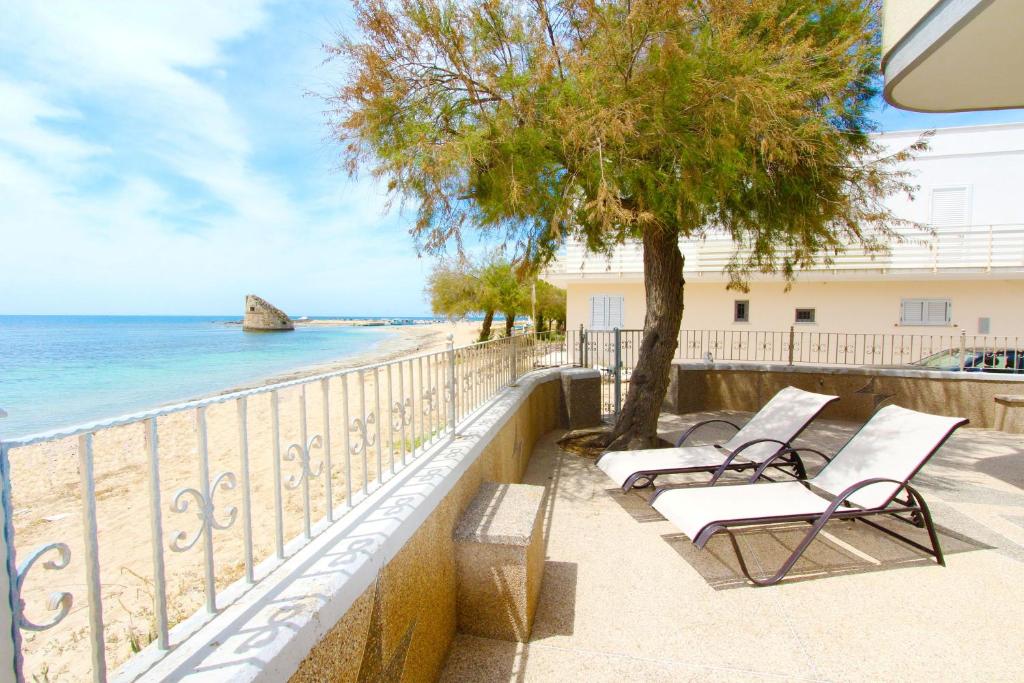 トッレ・パリにあるBeach house in Pugliaの木と海の景色を望むバルコニー(椅子付)