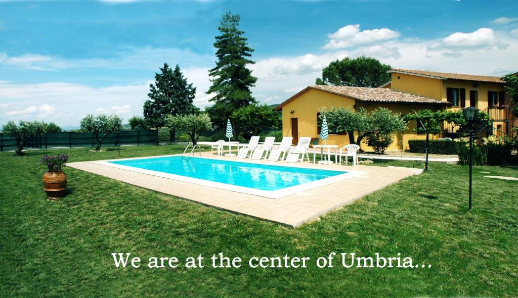 a yard with a pool with chairs and a house at Casale il Colle Deruta in Deruta