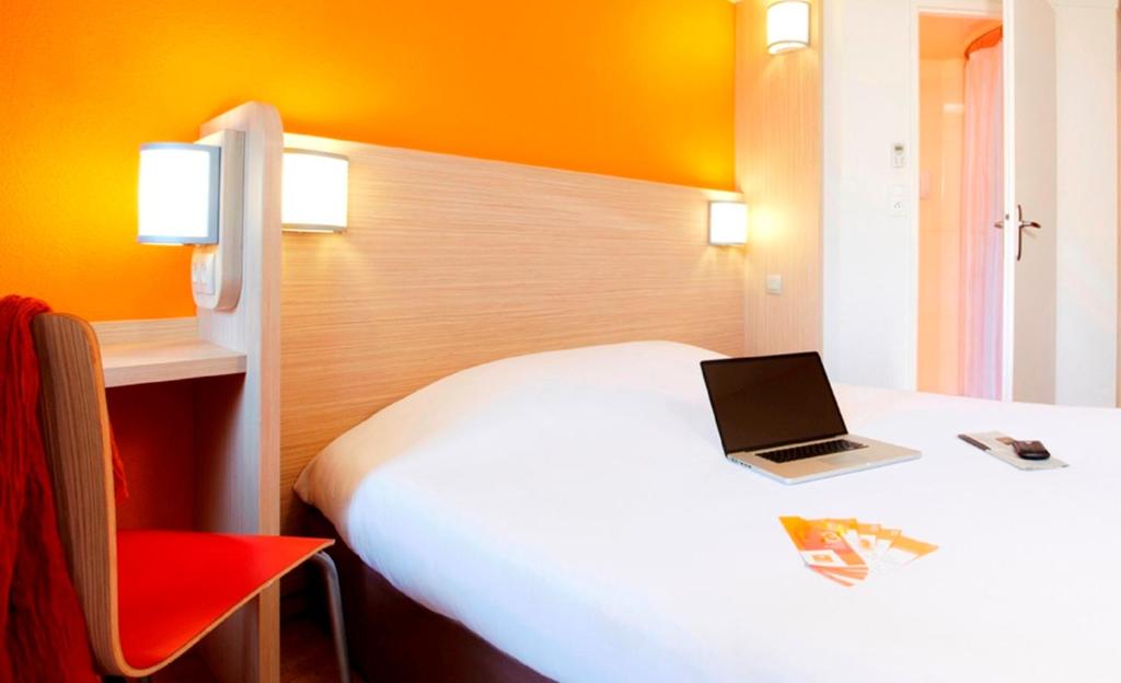 a hotel room with a bed with a laptop on it at Premiere Classe Caen Est - Mondeville in Mondeville