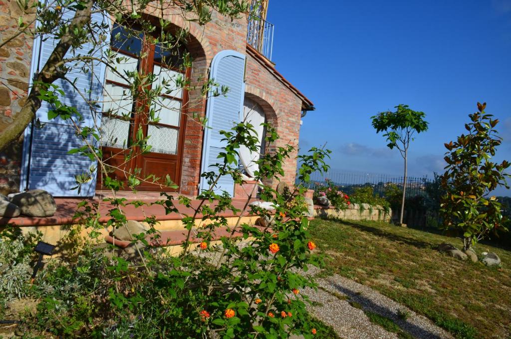a brick house with a red door and some flowers at Casa Magnolia in Terricciola