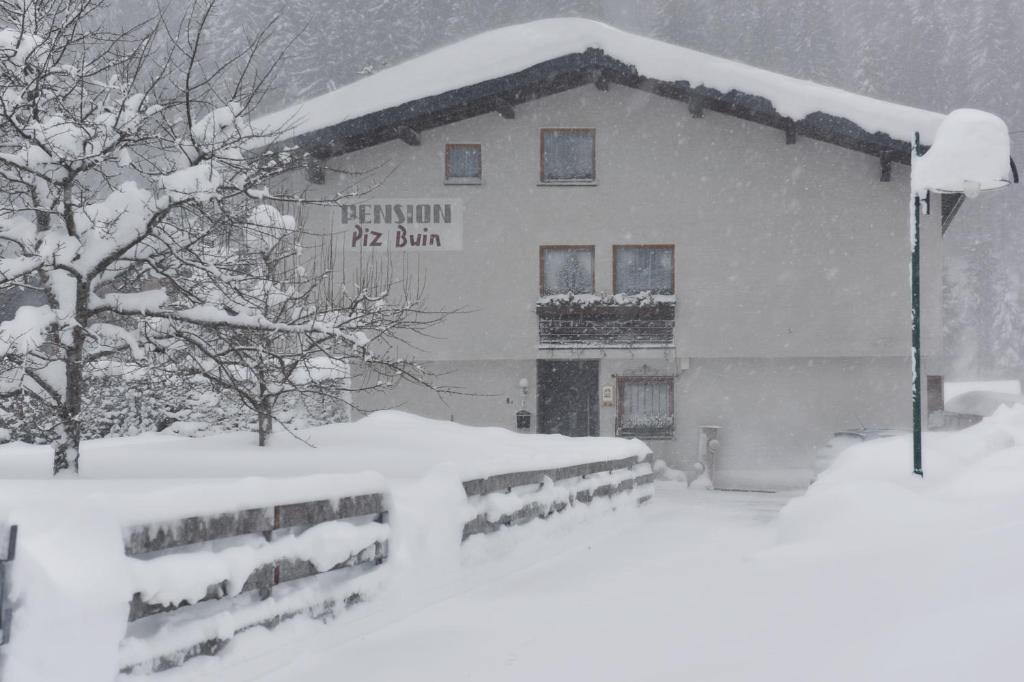 a building covered in snow with a sign on it at Pension Piz Buin in Partenen