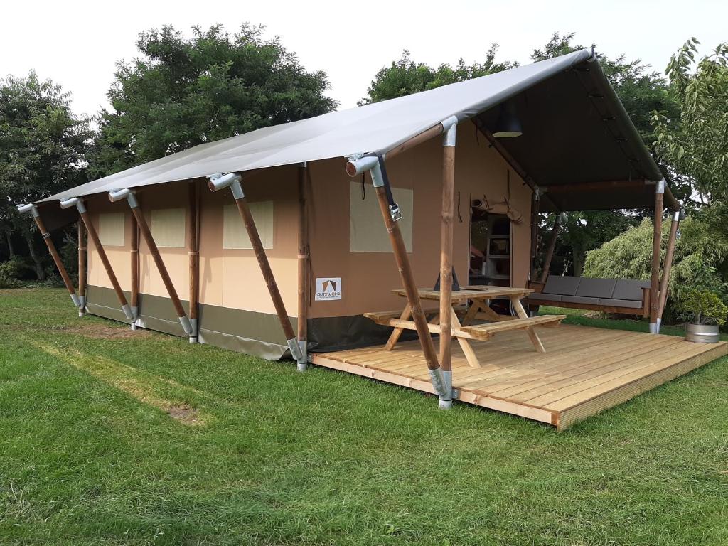 a large tent with a deck in the grass at Glamping tent Romala in Kiel