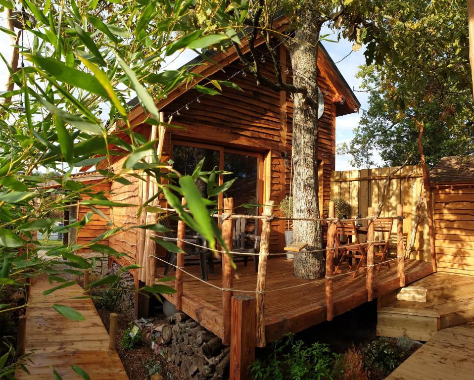 une cabane dans les arbres avec une terrasse et des chaises dans l'établissement Kabanéo - gîte et sauna- Samois sur Seine - Forêt de Fontainebleau, à Samois-sur-Seine