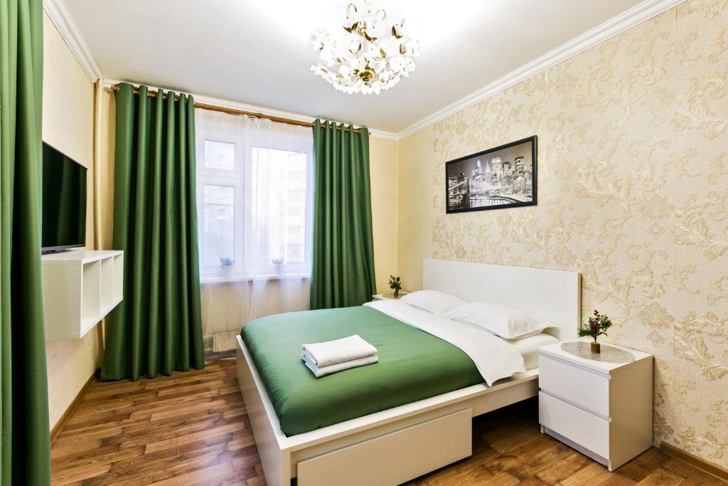 モスクワにあるApartament Hanaka Eletskaya 22/25のベッドルーム1室(緑のカーテンとシャンデリア付きのベッド1台付)