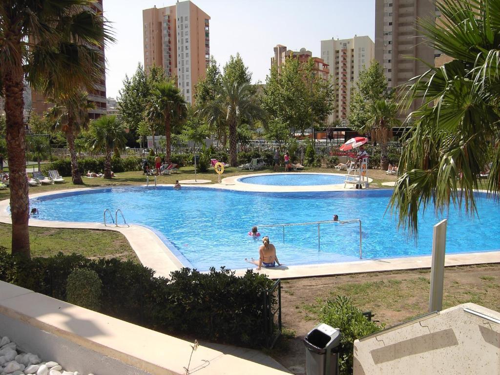 a large swimming pool in a city with people in it at Apartamentos con terraza Torre D'Oboe by Renthas in Benidorm