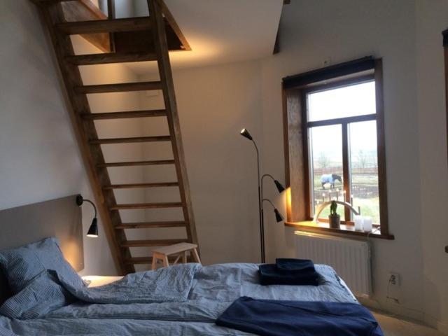 a bedroom with a bed with blue sheets and a staircase at Flyingehus Gårdshotell in Flyinge