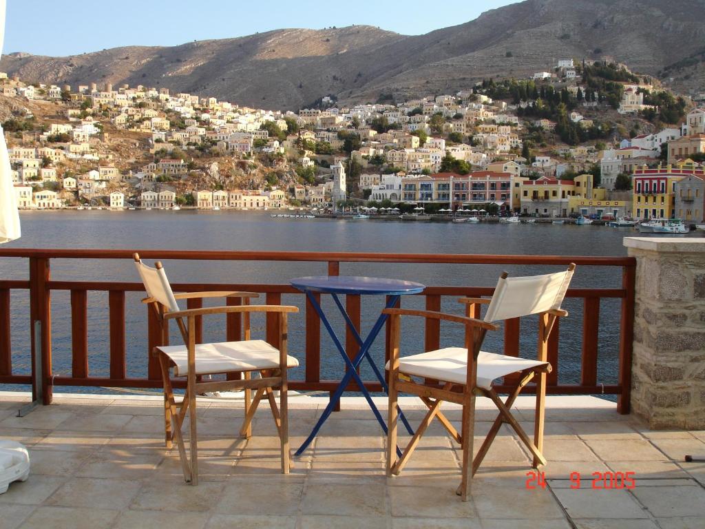 a table and chairs on a balcony overlooking a body of water at Odyssia in Symi