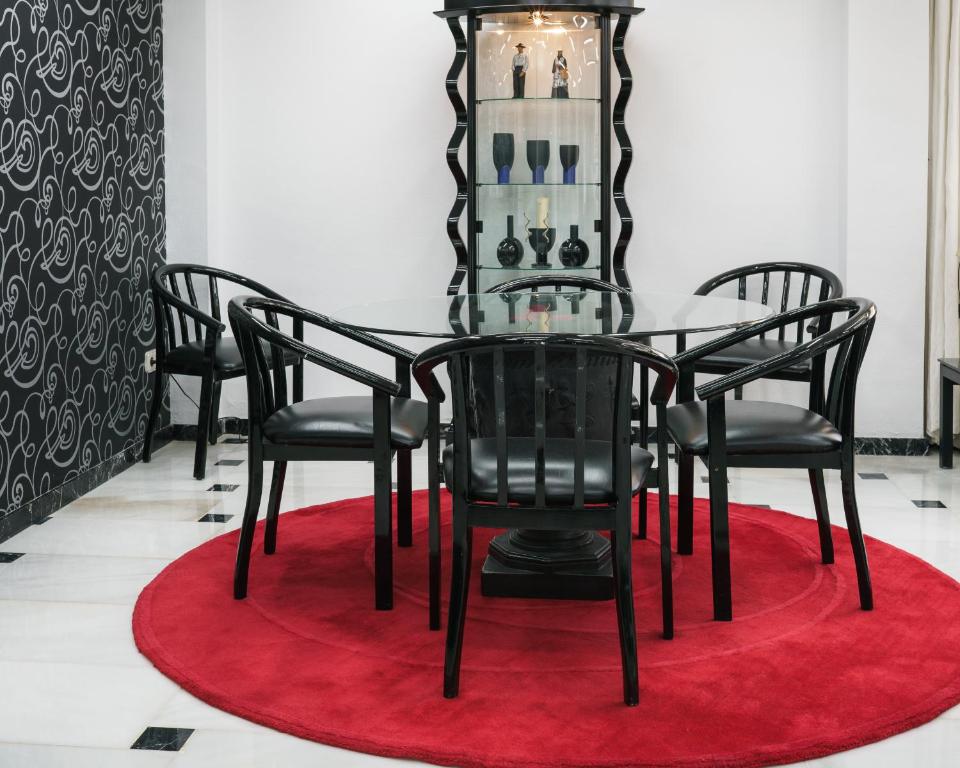 a dining room table with black chairs and a red rug at Hotel Albatros in Gandía