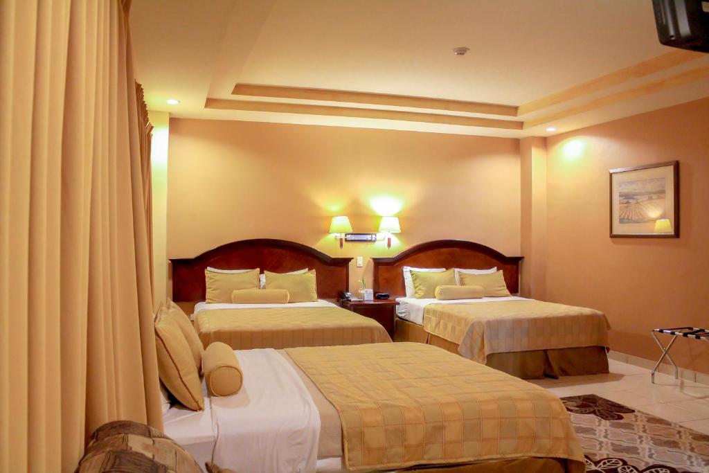 Habitación de hotel con 2 camas y cortinas en Hotel Monteolivos, en San Pedro Sula