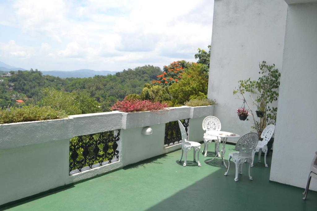 a balcony with a table and chairs and a view at Banda Casa, Kandy in Kandy