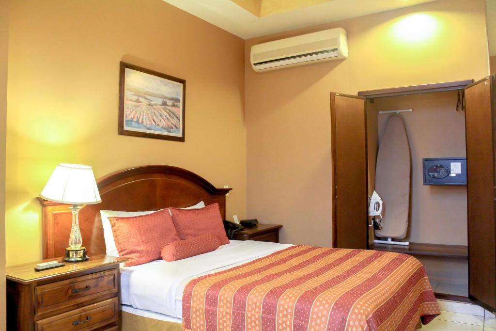 Una habitación de hotel con una cama y una lámpara. en Hotel Monteolivos, en San Pedro Sula