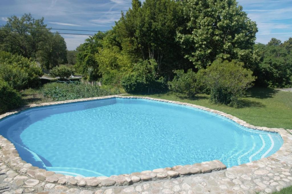 a large blue swimming pool with rocks around it at Masoveria la Roca in Sagás
