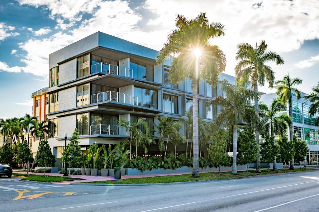 an apartment building with palm trees in front of a street at Urbanica Euclid in Miami Beach