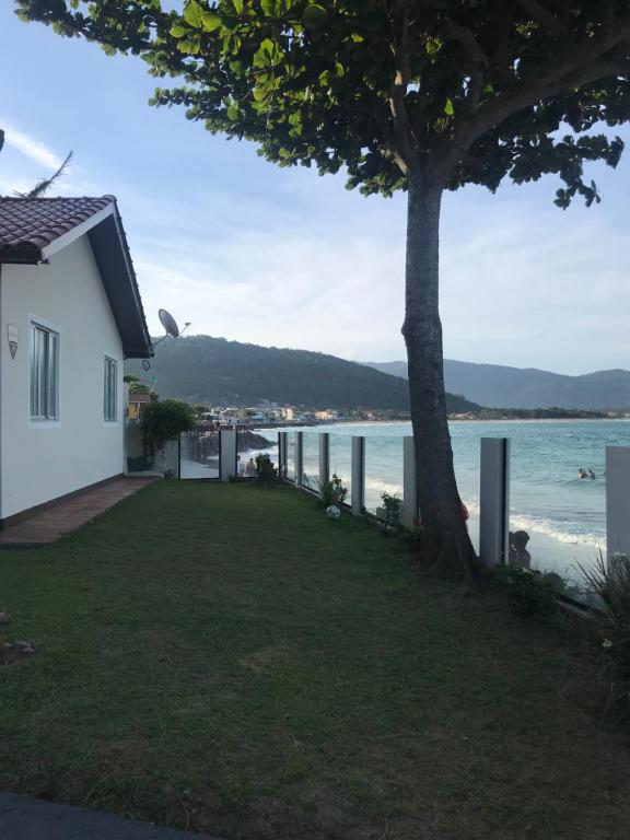 uma casa com uma árvore ao lado da água em Casa praia frente ao mar em Florianópolis