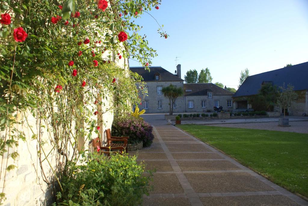a garden with red roses on a wall at Domaine Utah Beach - Le Grand Hard in Sainte-Marie-du-Mont