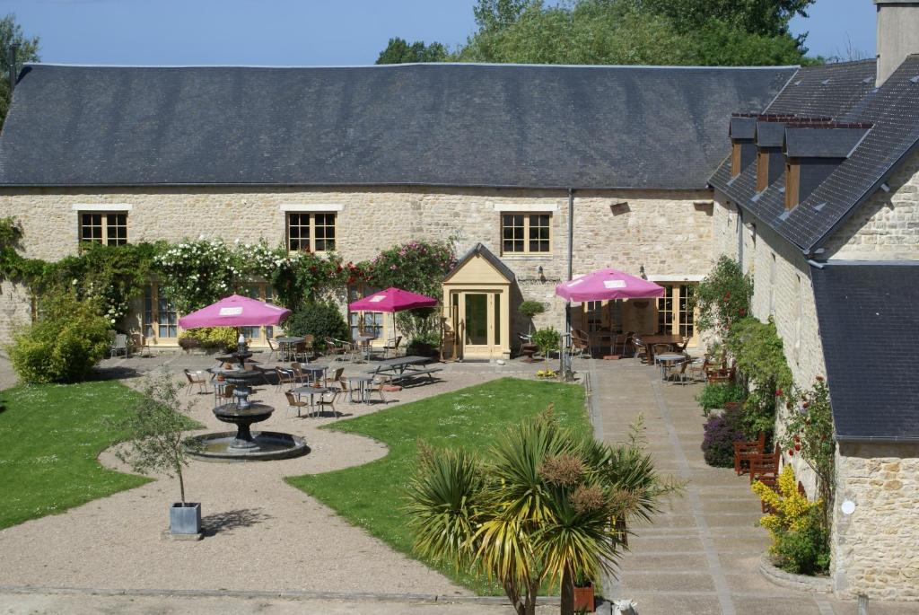 a building with tables and chairs and pink umbrellas at Domaine Utah Beach - Le Grand Hard in Sainte-Marie-du-Mont