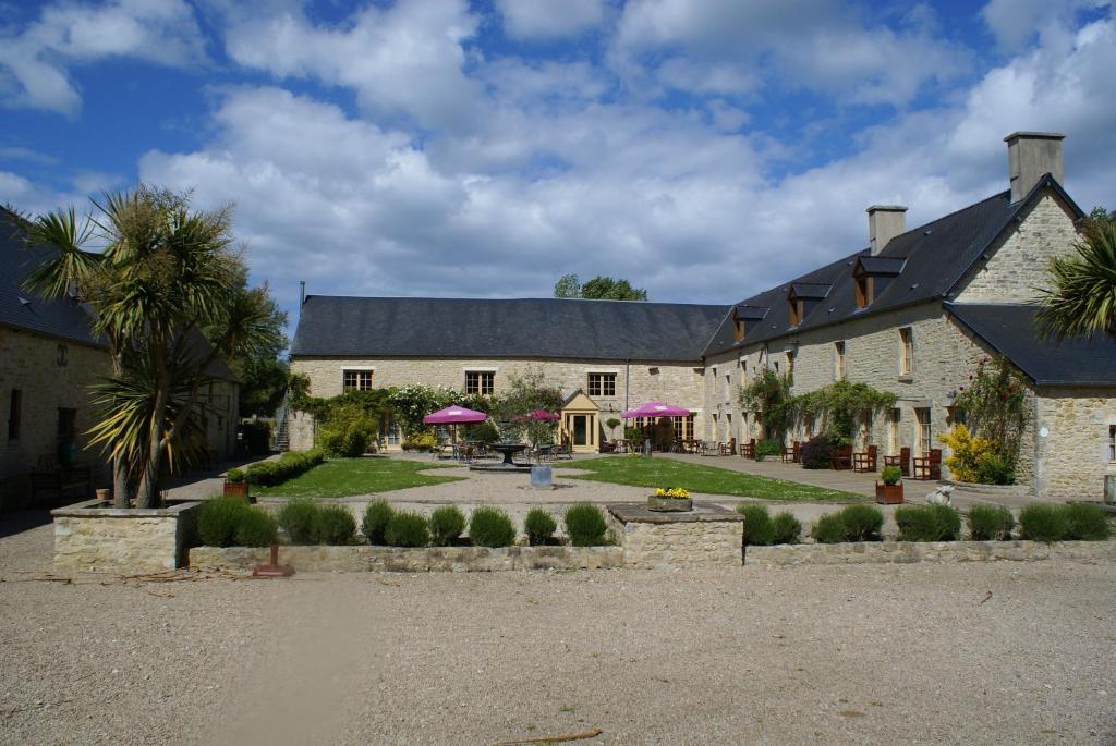 a large stone building with purple umbrellas at Domaine Utah Beach - Le Grand Hard in Sainte-Marie-du-Mont