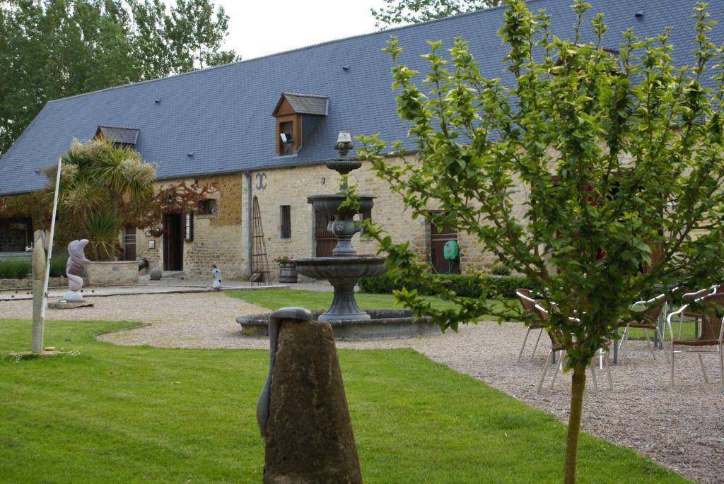 a building with a fountain in front of a yard at Domaine Utah Beach - Le Grand Hard in Sainte-Marie-du-Mont