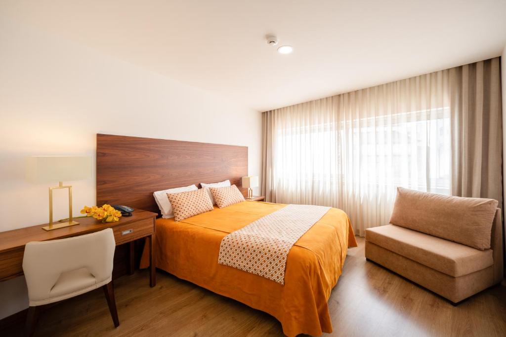 una camera con letto, scrivania e sedia di Hotel Nossa Senhora da Paz a Fátima