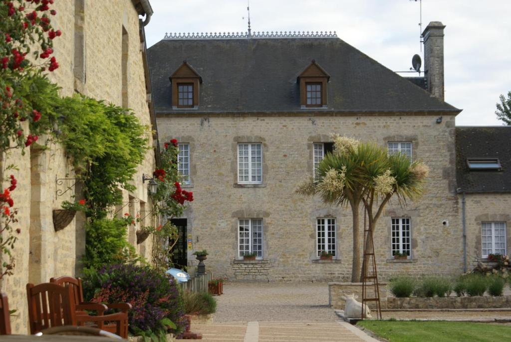 an old stone building with a palm tree in front of it at Domaine Utah Beach - Le Grand Hard in Sainte-Marie-du-Mont