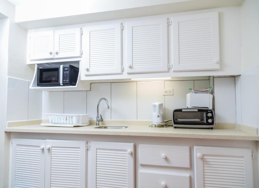 a kitchen with white cabinets and a sink and microwave at Crown Point Beach Hotel in Crown Point
