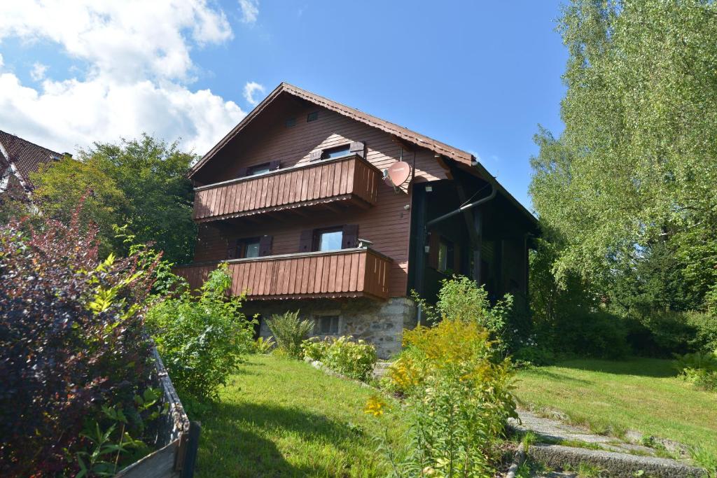 uma casa de madeira com uma varanda num quintal em Ferienwohnung Waldheimat 2 em Bayerisch Eisenstein