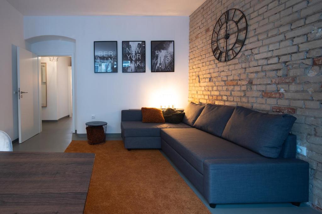 ein Wohnzimmer mit einem blauen Sofa und einer Ziegelwand in der Unterkunft Gemütliches Appartment südlich vom Wöhrder See in Nürnberg