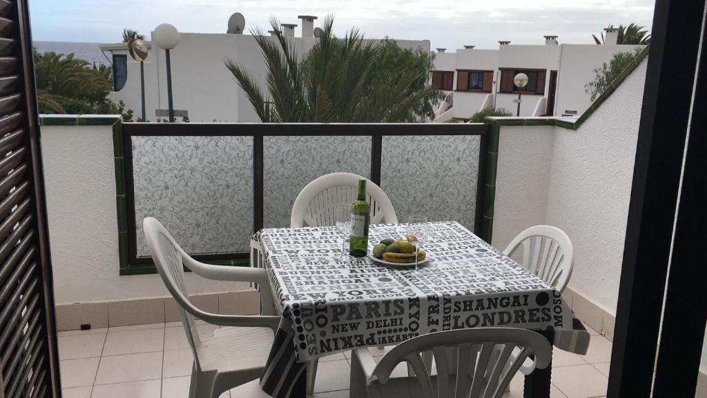 a table and chairs on a balcony with a bottle of wine at Calle Hesperides in Costa Del Silencio