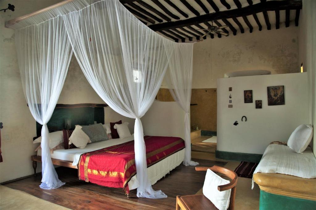 a bedroom with a canopy bed with curtains at Jardim dos Aloés, Unique B&B - Casa de Charme in Ilha de Moçambique