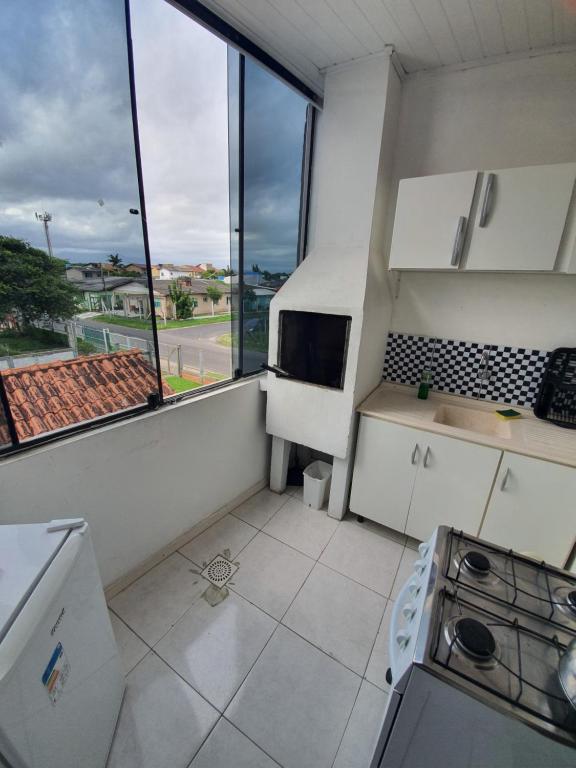 カパン・ダ・カノアにあるPousada do Primoの白い家電製品付きのキッチン、大きな窓