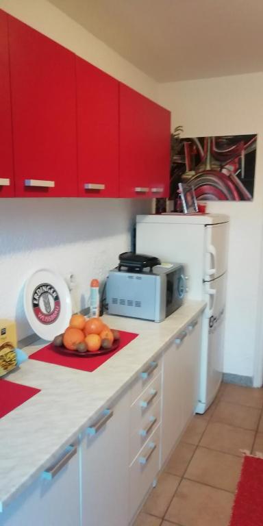 a kitchen with red cabinets and a plate of fruit on a counter at Apartment M&amp;A in Osijek