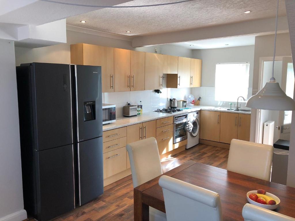 uma cozinha com um frigorífico preto e uma mesa de madeira em Bedzzz - House on the Green em Preston