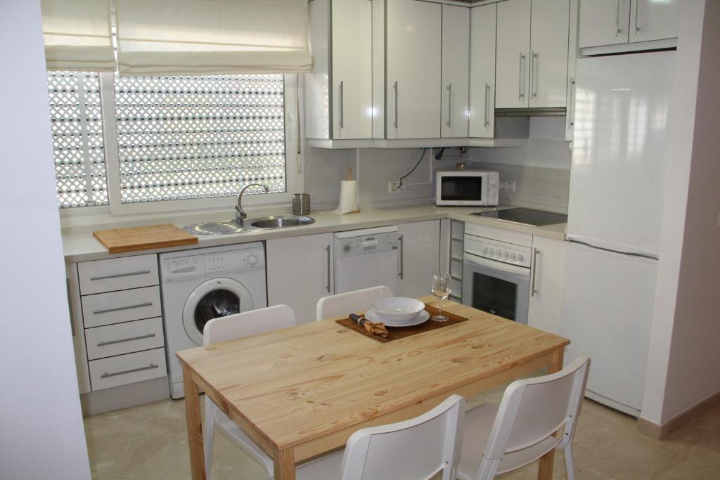 cocina con mesa de madera y armarios blancos en Apartamento Iris, en Córdoba