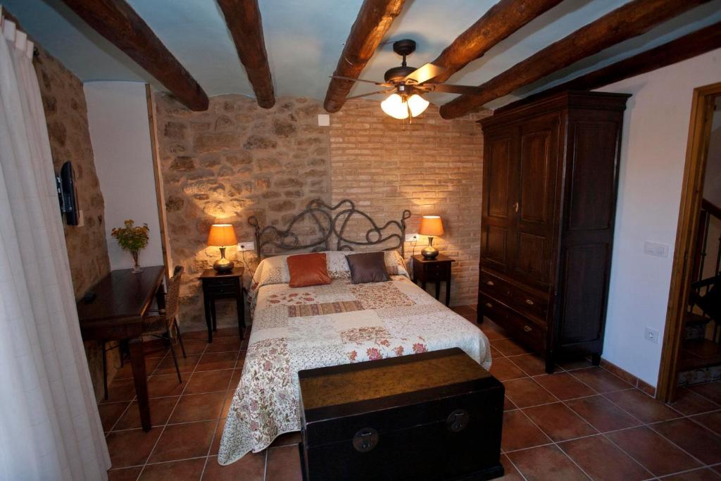 1 dormitorio con cama y pared de piedra en Casas Rural Calaceite, en Calaceite