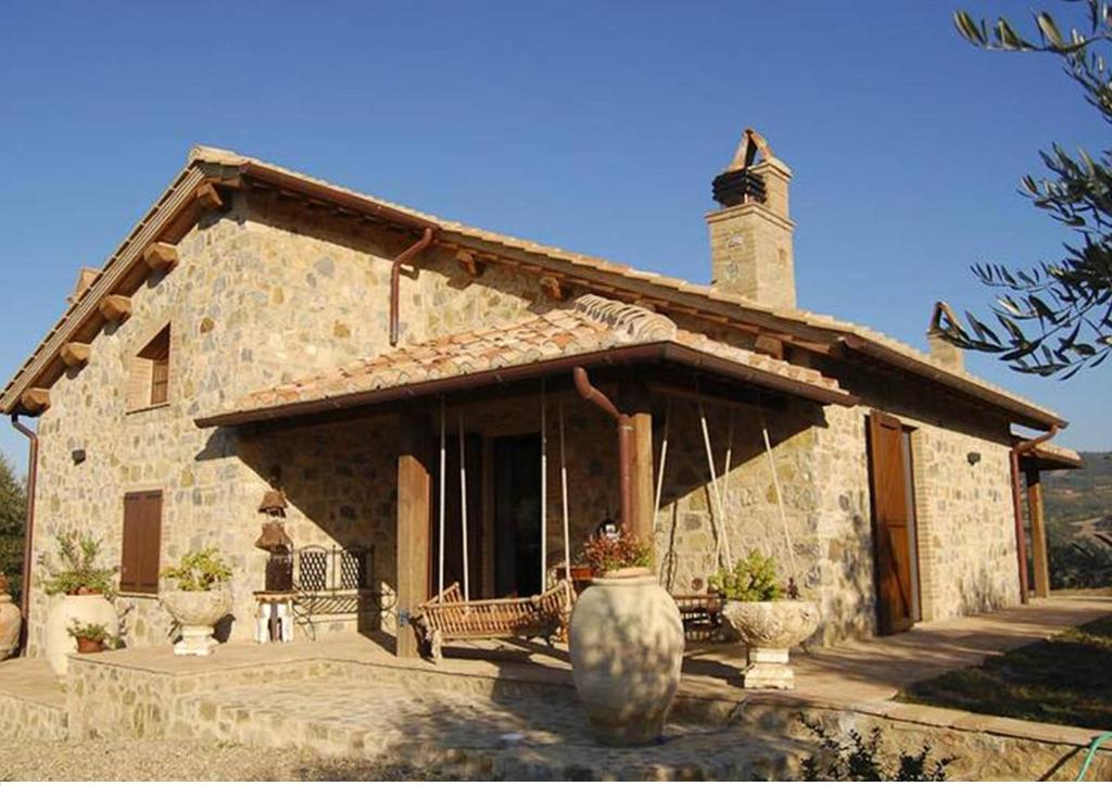a large stone house with a porch at Villa Poggio Aperto in Seggiano
