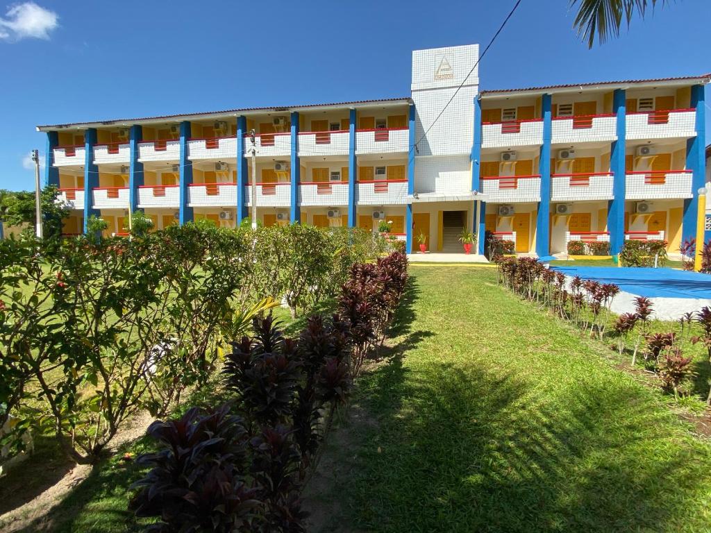 a large building with a swimming pool in front of it at Pousada das Acácias in Tamandaré