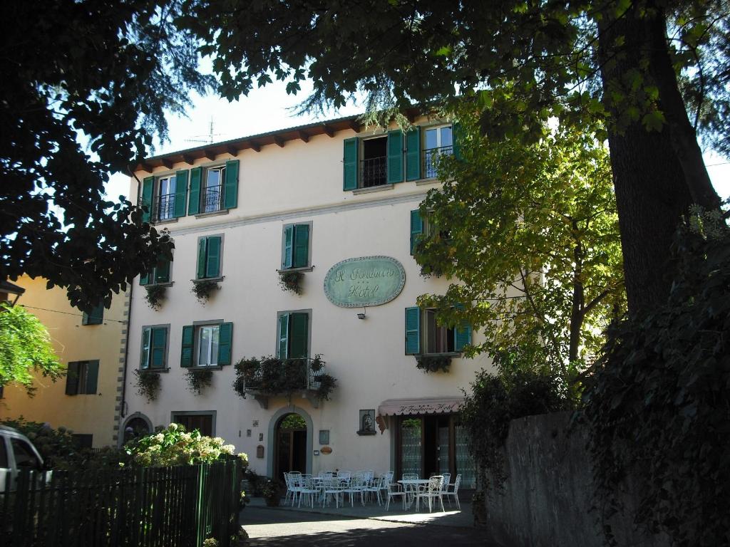 a building with green shutters and tables in front of it at Il Fondaccio in Lizzano in Belvedere