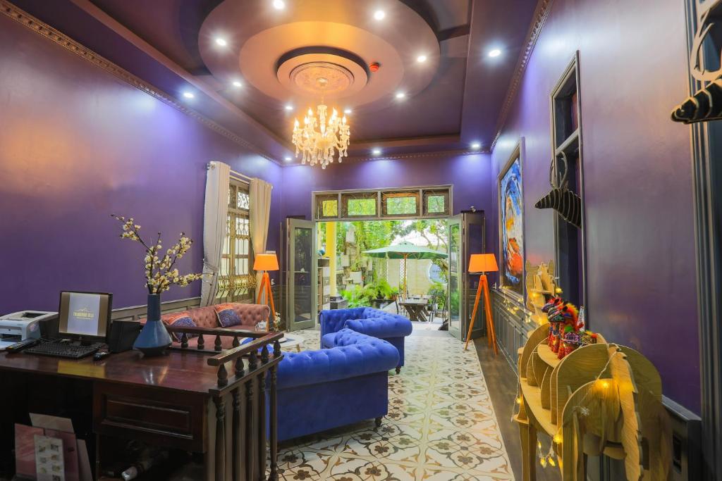 A vividly decorated living room combines purple walls, blue sofas and a garden-facing doorway.
