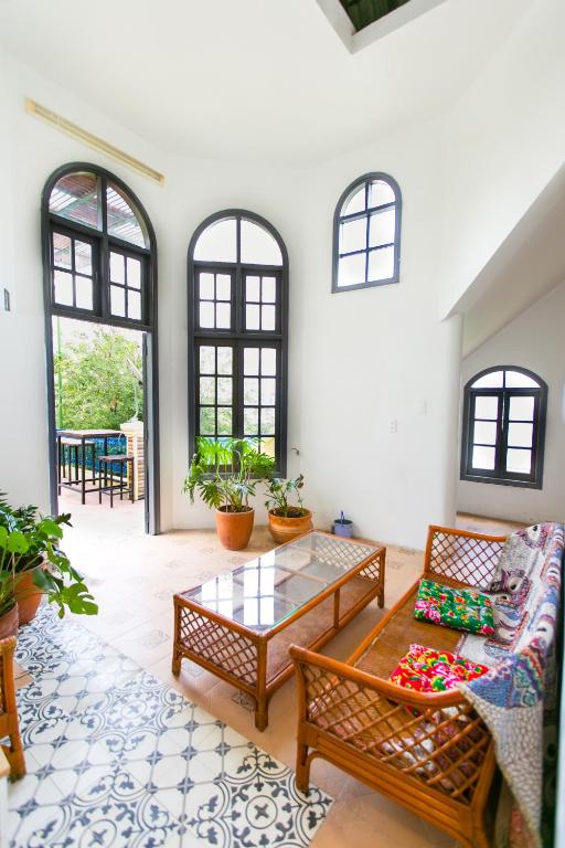 A bright sitting room combines rattan seating with tall arched windows.