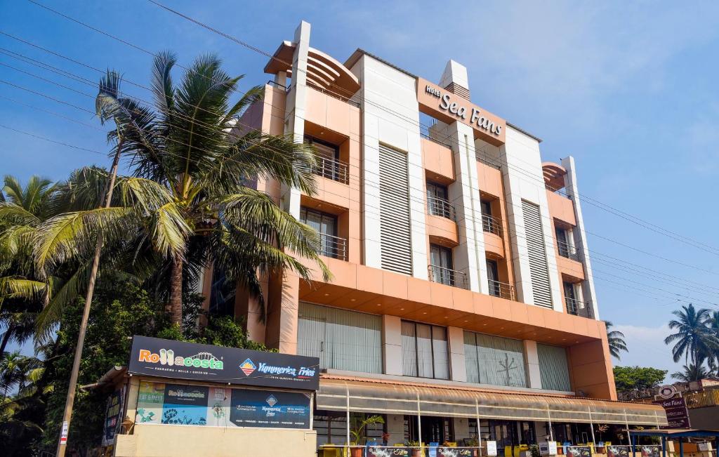 a building with a palm tree in front of it at Hotel Sea Fans in Ratnagiri