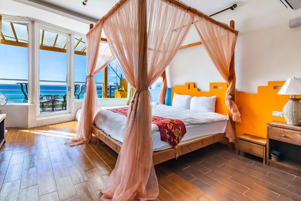 a bedroom with a canopy bed with a view of the ocean at Fei Li Jin Hotel in Kenting