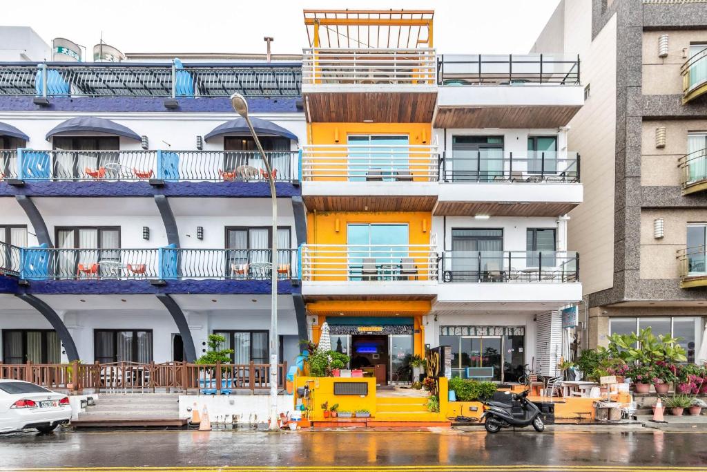a yellow building with balconies and a scooter parked in front at Fei Li Jin Hotel in Kenting