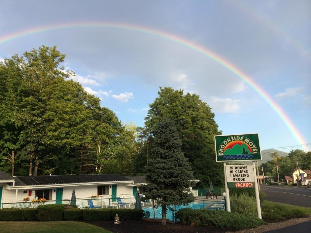 Ein Regenbogen am Himmel über einem Haus mit einem Schild in der Unterkunft Brookside Motel & Cabins in Lake George