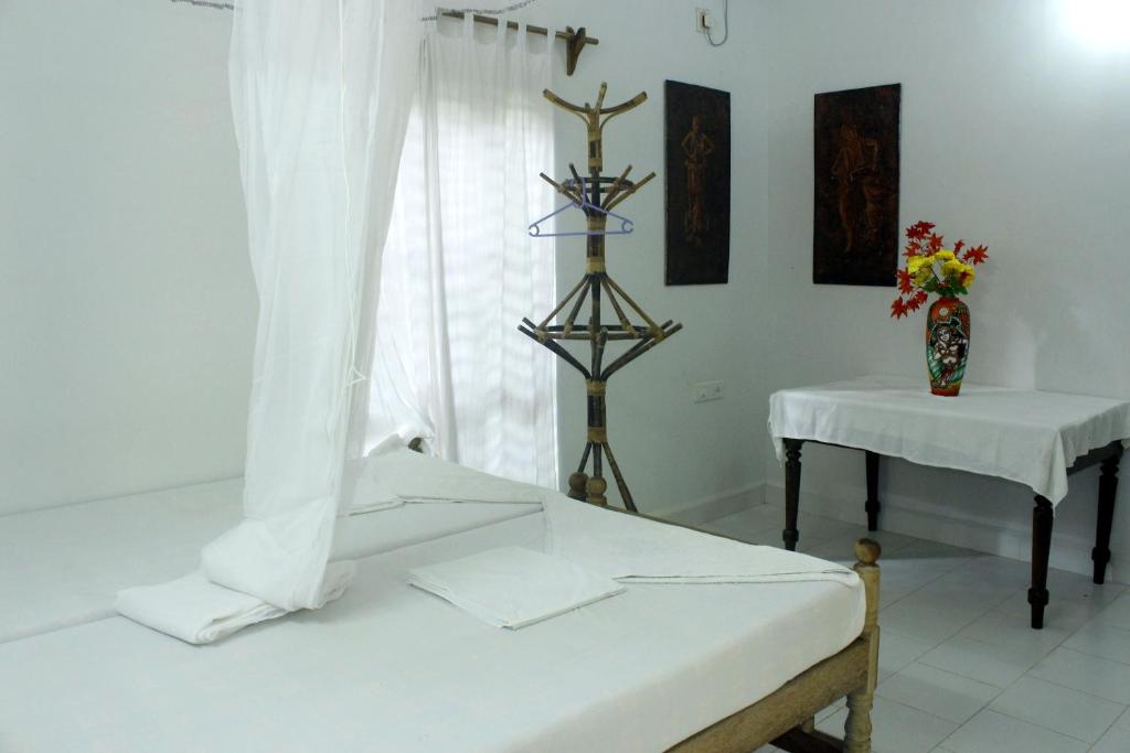 a room with a bed and a table and a window at Jickys Nest in Varkala