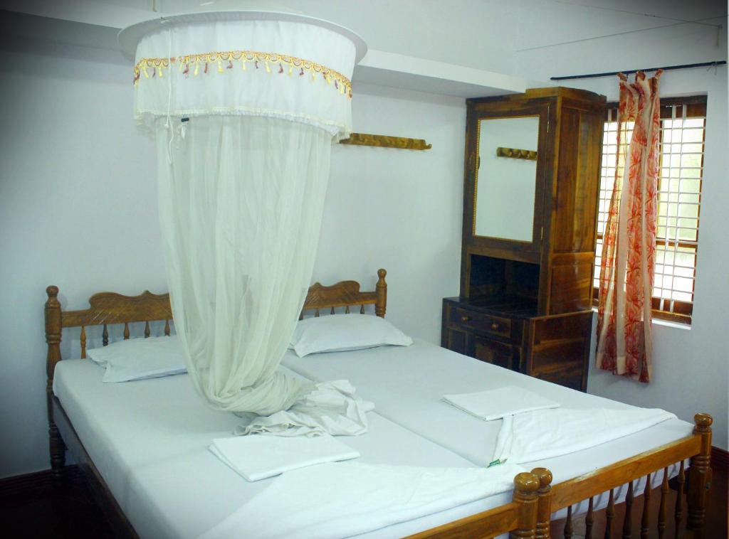 a bedroom with a bed with a canopy and a mirror at Jickys Nest in Varkala