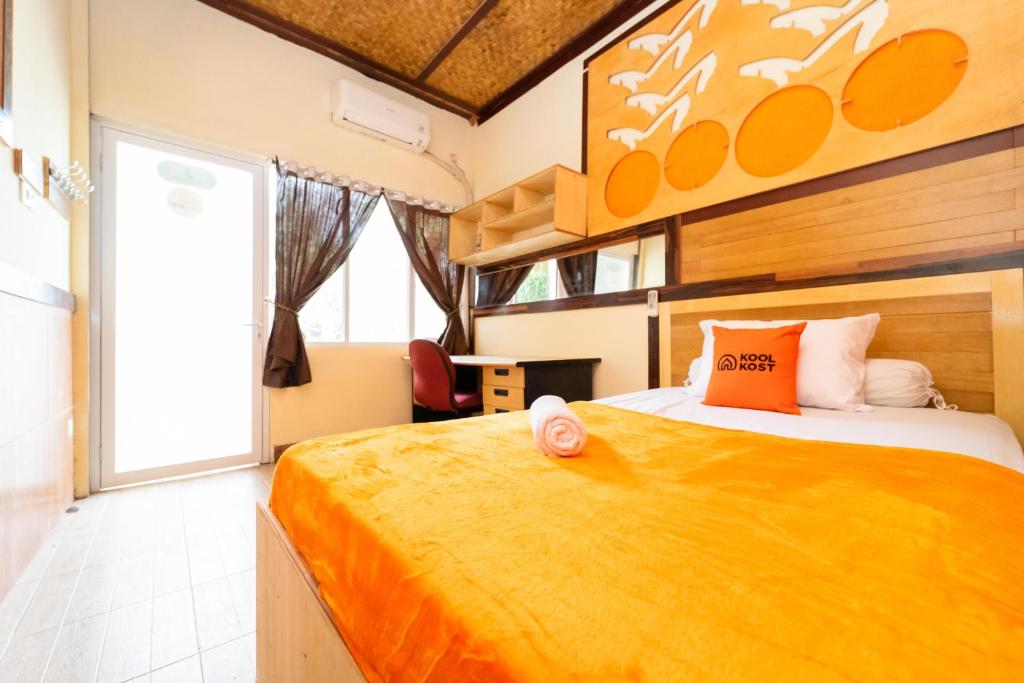 a bedroom with a large bed with an orange blanket at KoolKost near University of Indonesia in Pondoktjing Dua