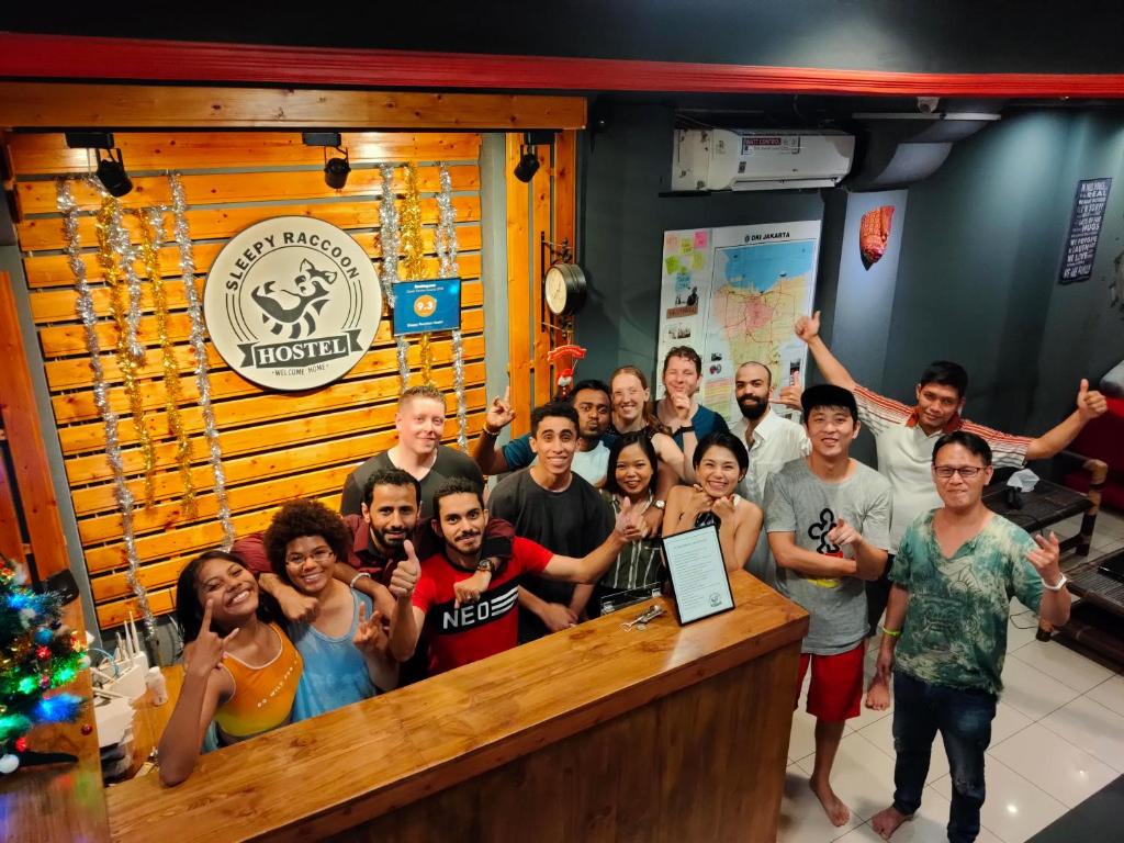 a group of people posing for a picture at a bar at Sleepy Raccoon Hostel in Jakarta